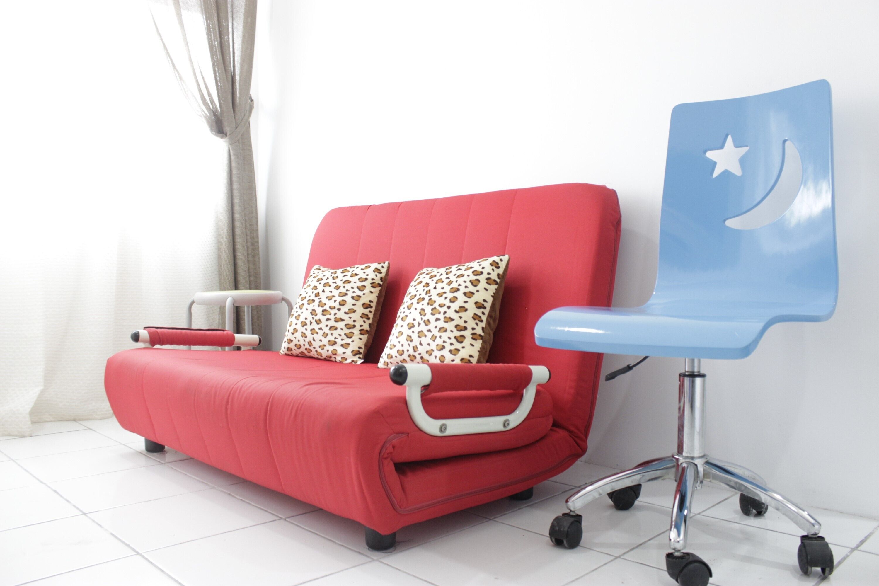 Un sofá rojo con un sillón a juego, ambos con un tirador, y una mesita auxiliar al lado.