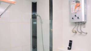 A bathroom with a glass shower enclosure, a wall-mounted instant heater, and a control panel. - Comfy with Modern Style 1BR Grand Kamala Lagoon Apartment (Bekasi)