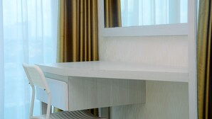A white desk with a chair, a window with curtains, and a view of the outside. - Comfy with Modern Style 1BR Grand Kamala Lagoon Apartment (Bekasi)