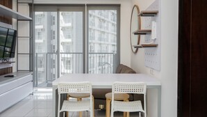 A modern kitchen with a dining area, large windows, and a TV on the left. - Premium Relaxing 2BR at Casa de Parco Apartment (South Tangerang)