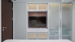 A bedroom with a bed, a TV mounted on a wall, and a wardrobe with frosted glass doors. - Premium Relaxing 2BR at Casa de Parco Apartment (South Tangerang)