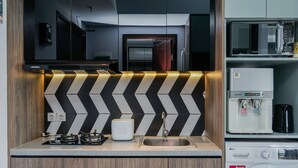 Una cucina moderna con zoccolo a V bianco e nero, lavello in acciaio inossidabile e lavatrice integrata.