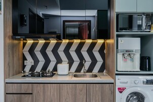 Una cocina moderna con un salpicadero blanco y negro tipo chevron, un lavamanos de acero inoxidable y una lavadora integrada.