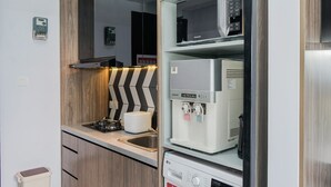 Un angolo cottura compatto con forno a microonde integrato, macchina del caffè e un piccolo lavello.