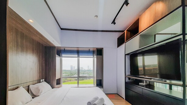 Una moderna camera d'albergo con un grande letto, una televisione a schermo piatto e vista sulla città.