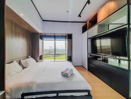 Una habitación de hotel moderna con una cama grande, un televisor de pantalla plana y vistas a la ciudad.