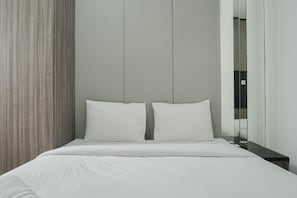 Una habitación de hotel moderna con una cama grande, una mesita de noche y un espejo.