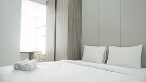 Une chambre d’hôtel moderne avec un grand lit, une armoire en bois et une fenêtre laissant entrer la lumière naturelle.