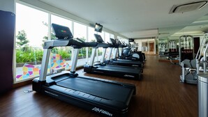 Een sportschool met meerdere loopbanden, hometrainers en krachtapparaten.