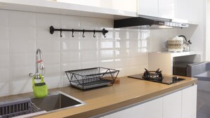Eine moderne Küche mit weißen Schränken, einer Edelstahl-Spüle, einem schwarzen Hängegestell und einem kleinen Kaktus auf der Arbeitsfläche.