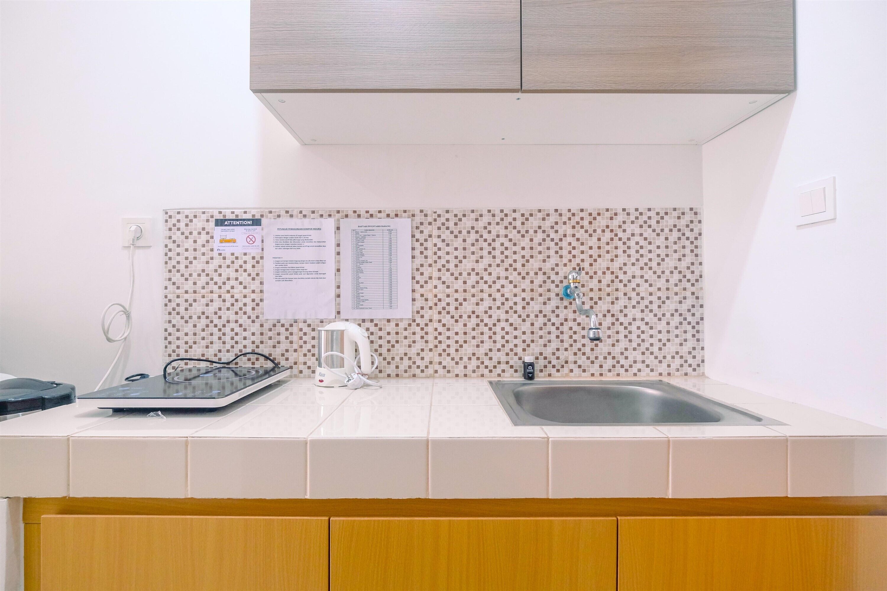 Una cocina con salpicadero de azulejos, un lavamanos, un hervidor y una balanza.