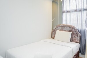 Una cama individual con colchón blanco y cabecera decorativa.