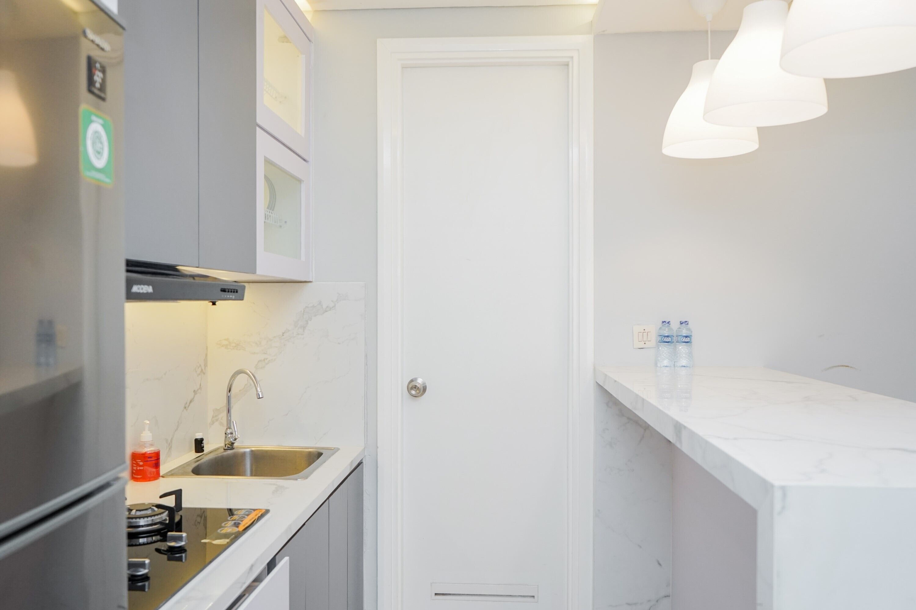 Une cuisine moderne équipée d’une cuisinière intégrée, d’un évier et d’une porte blanche.