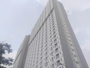 A tall, modern building with a grid-like facade and numerous windows. - Beautiful Studio at Gunung Putri Square Apartment (Gunung Putri)