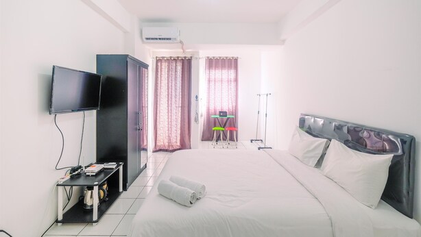 A hotel room with a bed, a TV, a desk, and a chair.