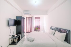 Une chambre d’hôtel avec un lit, une télévision, un bureau et une chaise.