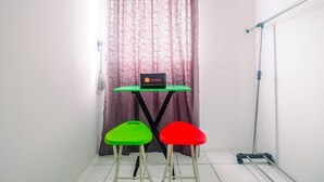 A small room with a table, two stools, a curtain, and a cleaning tool.