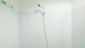 A shower with a handheld showerhead in a tiled bathroom.