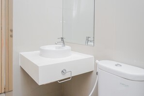 A modern bathroom with a white sink, mirror, and toilet.