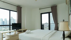 Una habitación de hotel con cama, televisión, escritorio y vistas a la ciudad.