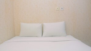 A bed with white bedding and pillows, a plain wall with a subtle pattern, and a power outlet on the wall. - Cozy Living with Modern Design 1BR Kebagusan City Apartment (Jakarta)