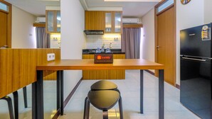 A modern kitchen with wooden cabinets, a black refrigerator, and a travel sign on the counter. - Comfortable 2BR Apartment at Cinere Resort (Depok)