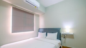A neatly made bed with white linens, a bedside table with a lamp, and a wall-mounted air conditioner. - Comfortable 2BR Apartment at Cinere Resort (Depok)