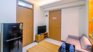 A compact hotel room with a kitchenette, a flat-screen TV, a sofa, and a coffee table. - Comfortable 2BR Apartment at Cinere Resort (Depok)