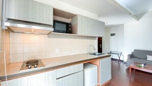 A compact kitchen with a microwave, stove, and sink. - 1BR Queen Bed at Ancol Marina Apartment near Dufan (Jakarta)