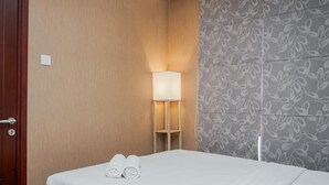 A hotel room with a bed, a nightstand with a lamp, and a patterned wall. - Gorgeous and Relaxing 1BR Asatti Apartment (Pagedangan)