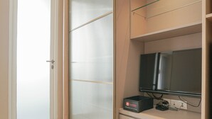 Ein Zimmer mit einer Schiebeglasdoor, einem an der Wand montierten Flachbildfernseher und einer Steckleiste mit einer Box mit dem Aufdruck 'Travelio'.