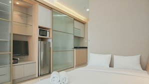 Ein modernes Hotelzimmer mit Bett, Fernseher, Kühlschrank und Mikrowelle.
