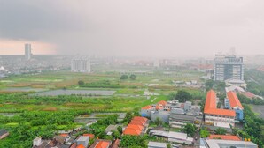 Un paysage urbain mêlant des immeubles résidentiels et commerciaux, un vaste plan d’eau et un ciel nuageux.