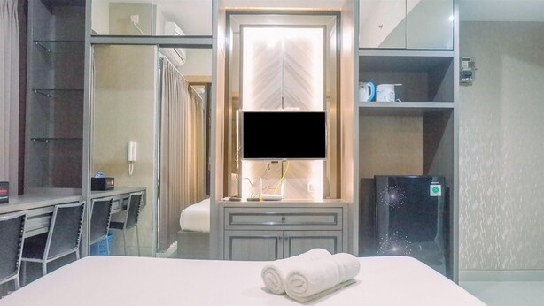 Une chambre d’hôtel équipée d’un lit, d’un bureau, d’une télévision, d’un miroir et d’une armoire.