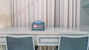 Une chambre d’hôtel équipée d’un bureau, de deux chaises et d’un minibar orné du logo Travelio.
