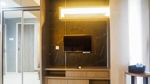 Ein modernes Badezimmer mit einem großen Spiegel, einem Waschtisch und einem Fernseher, der an einer Marmorwand angebracht ist.