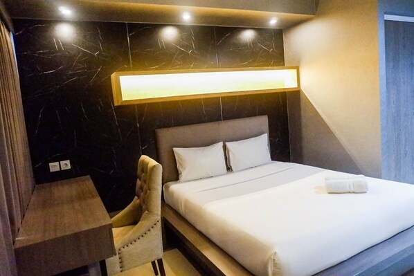 Moderni hotellihuone, jossa on suuri sänky, yöpöytä ja tuoli.