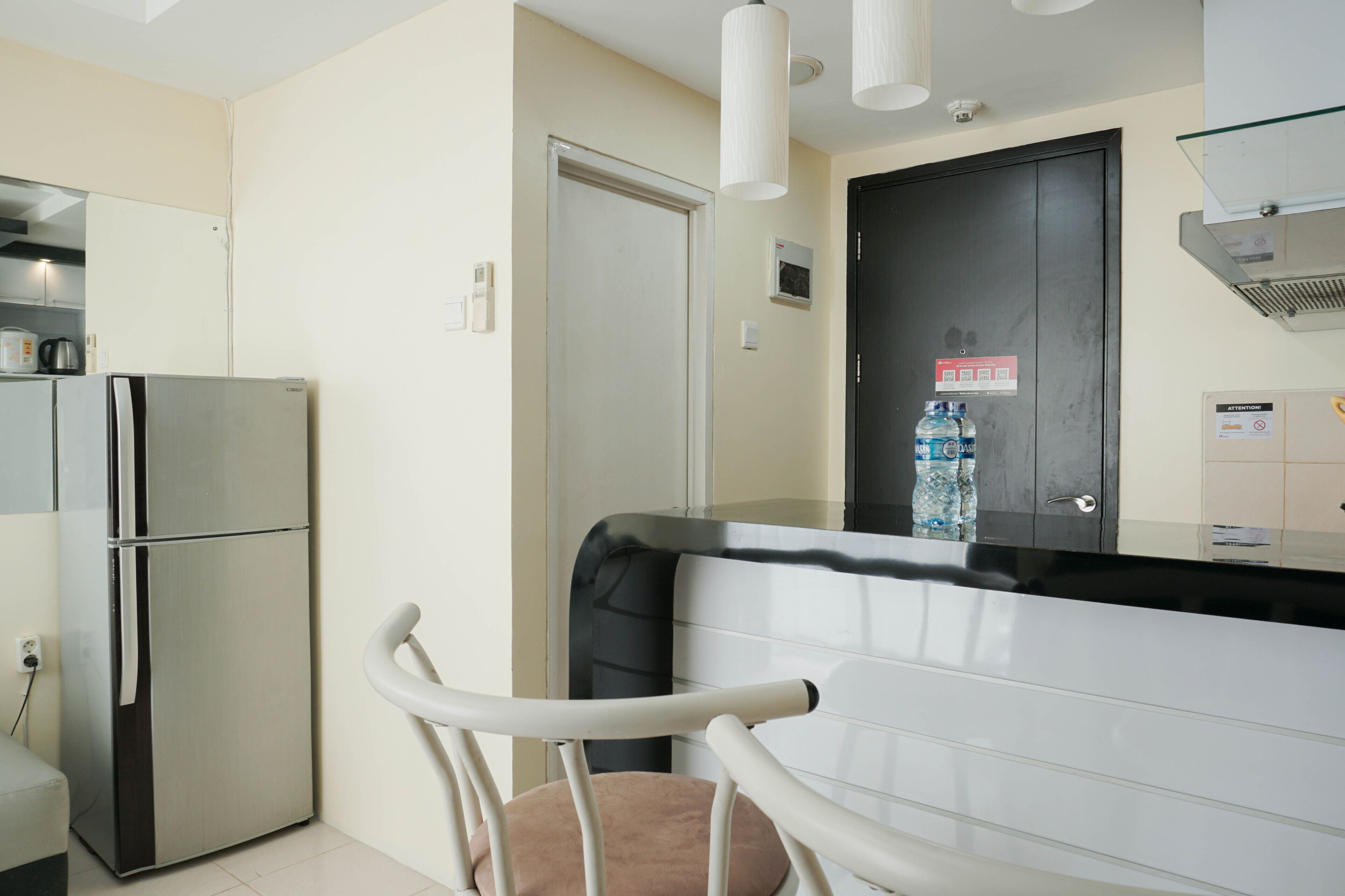 A modern kitchen with a stainless steel refrigerator, a white countertop, and a black door.
