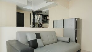 Una sala de estar moderna con un sofá gris, una almohada blanco y negro, y un refrigerador gris.