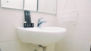 Een wastafel met een spiegel erboven, een handdoekhouder en twee tandenborstels op de wastafel.