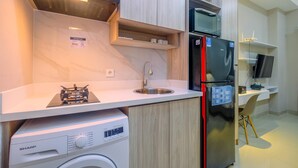 A modern kitchen with a built-in washing machine, a stainless steel refrigerator, and a microwave. - Homey and Warm Studio Apartment Oasis Cikarang (Cikarang)
