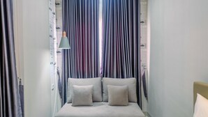 A room with a bed, a hanging lamp, and curtains with a newspaper print design. - Homey and Warm Studio Apartment Oasis Cikarang (Cikarang)