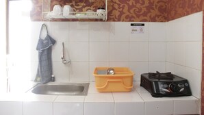A kitchen with a sink, a dish rack, a gas stove, and a storage bin. - Minimalist 2BR Apartment at Gateway Ahmad Yani Cicadas (Bandung)