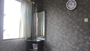 A room with a window, striped curtains, a mirror, a clock, and patterned wallpaper. - Minimalist 2BR Apartment at Gateway Ahmad Yani Cicadas (Bandung)
