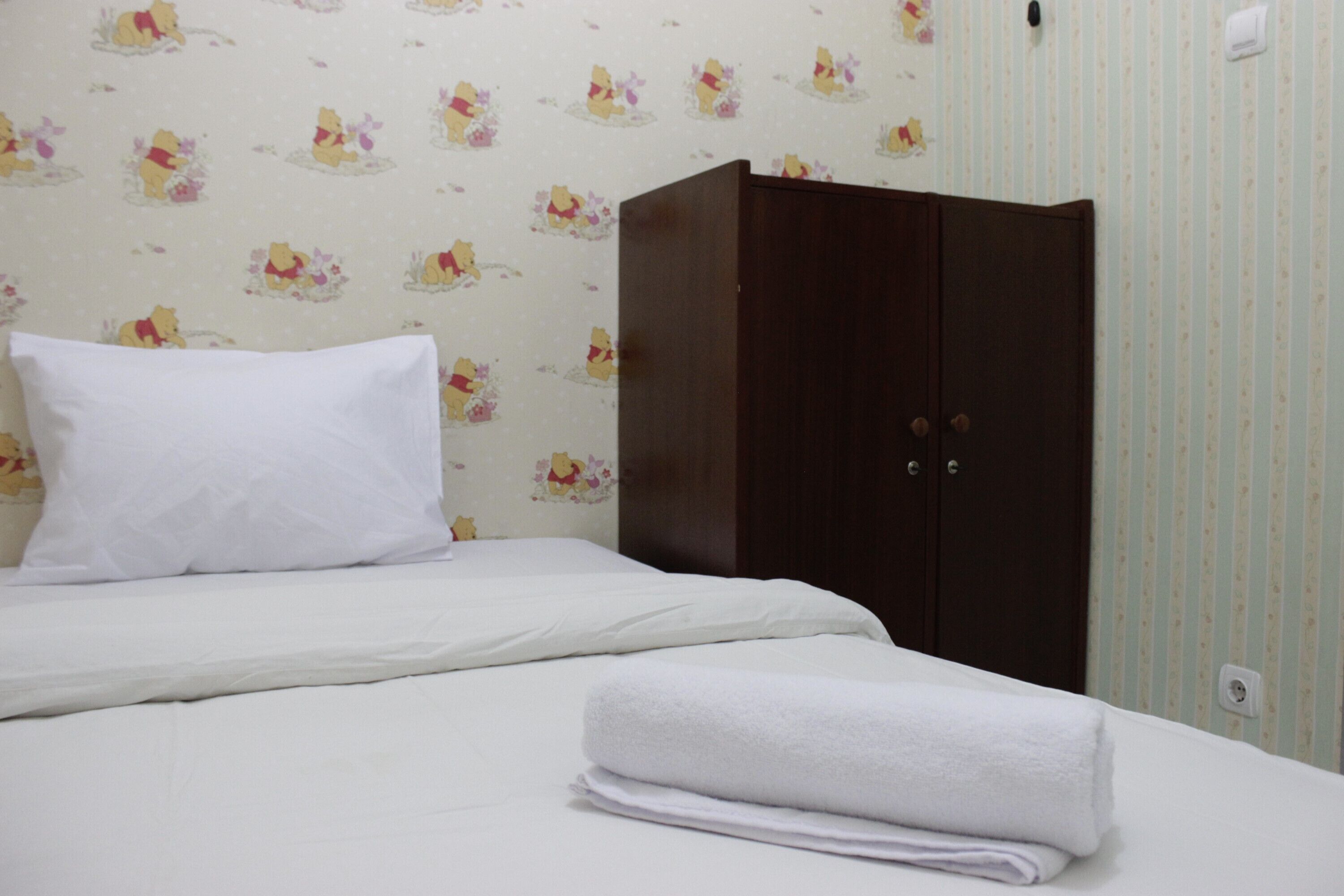 A neatly made bed with white linens, a white pillow, and a folded white towel.