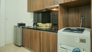 A kitchen with wooden cabinets, a stainless steel refrigerator, a sink, and a water purifier. - Luxury Design 1BR L'Avenue Apartment near Pancoran (Jakarta)