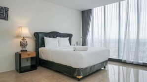 A modern hotel room with a large bed, a nightstand with a lamp, and a city view through sheer curtains. - Luxury Design 1BR L'Avenue Apartment near Pancoran (Jakarta)