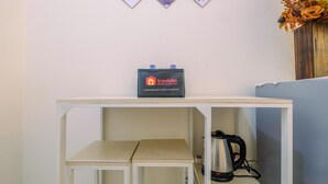 A kitchenette with a travelio branded battery pack, a kettle, and a small table. - New Room Studio at Green Pramuka Apartment (Jakarta)