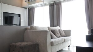 Ein modernes Wohnzimmer mit einer Couch, einem Hocker und einem flachbildfernseher an der Wand.