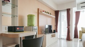 A modern hotel room with a flat-screen TV, a minibar, a green decorative item, and a "LOVE" sign on the wall. - Elegant and Relaxing Studio Apartment H Residence (Jakarta)
